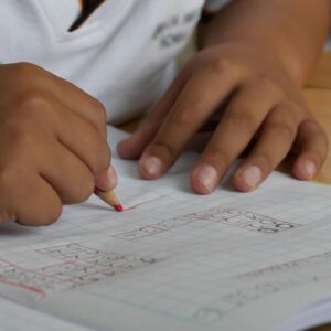Close-up of a student writing math equations in a notebook with a pencil indoors.